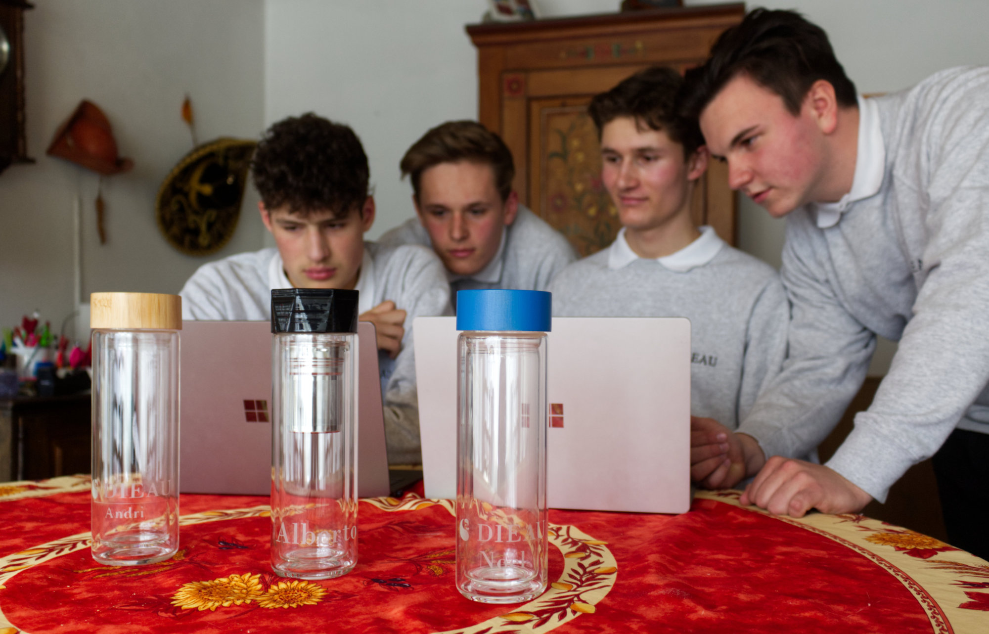 Vier Jungunternehmer hinter dem Laptop. Im Vordergrund die DIEAU doppelwandige Glastrinkflasche.