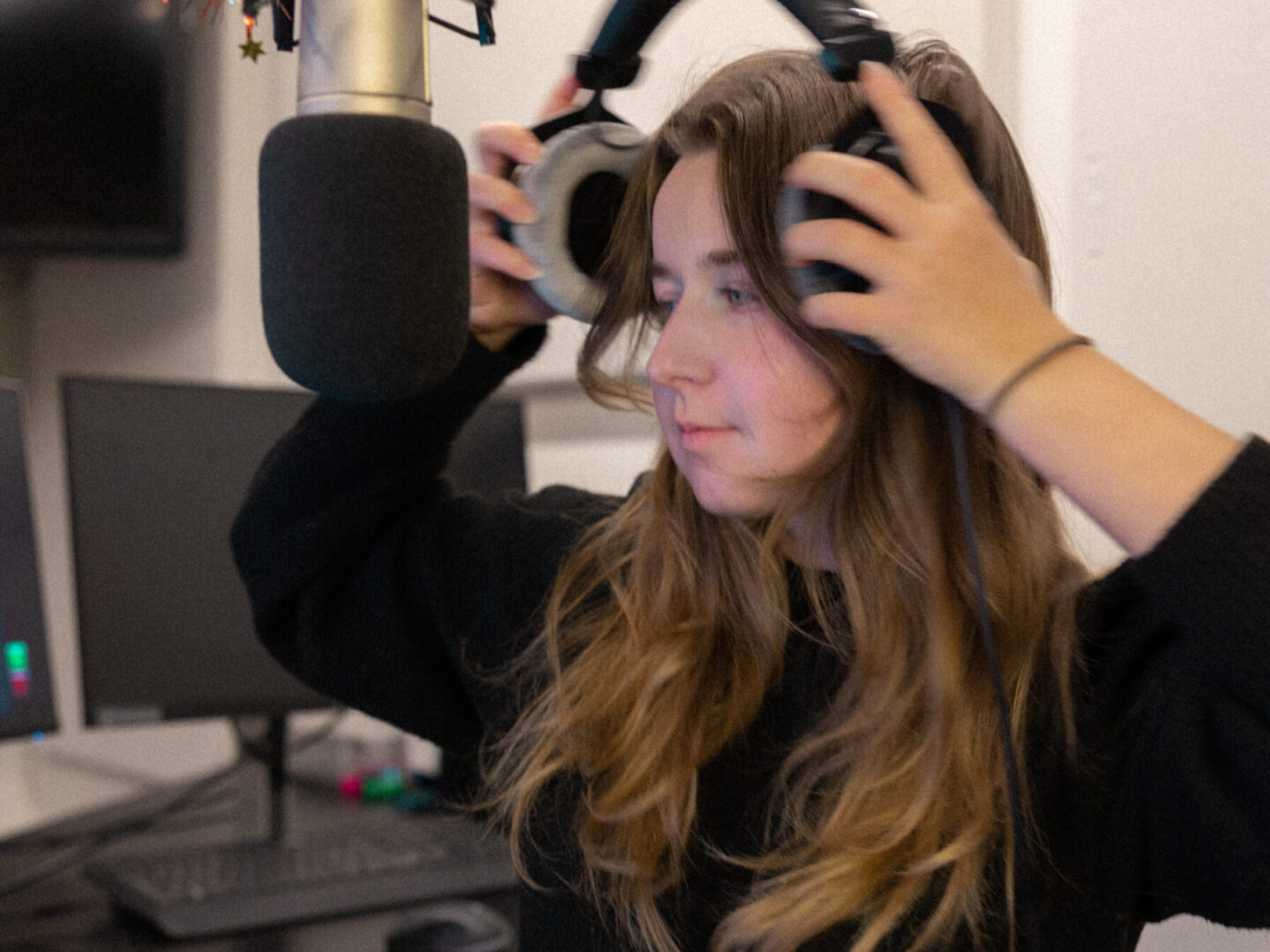 lisan (she/her) in a radio studio putting headphones on